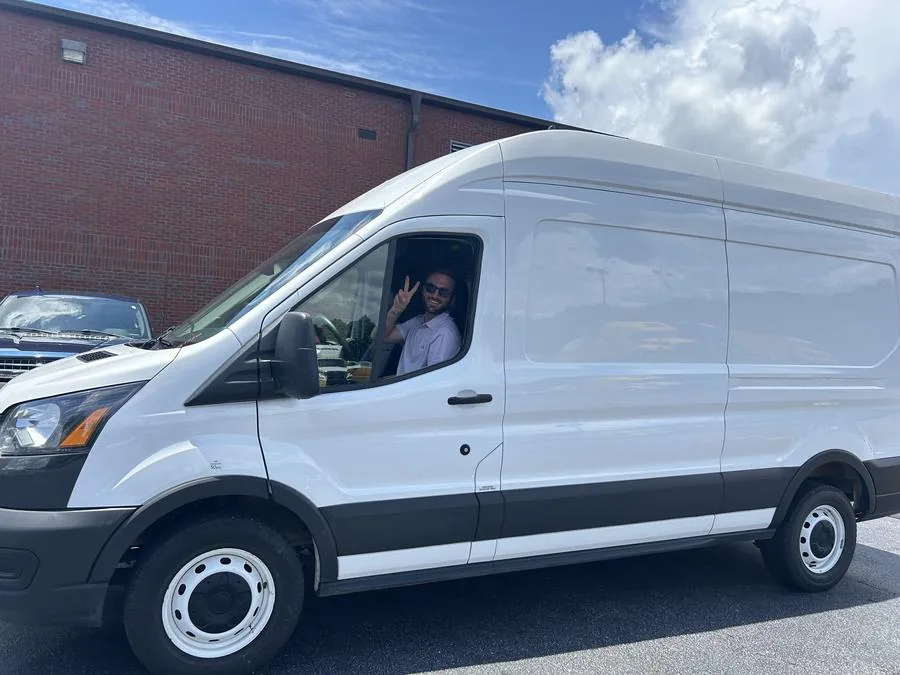 Mason Gooch waving from the driver's seat of the first Harvest van